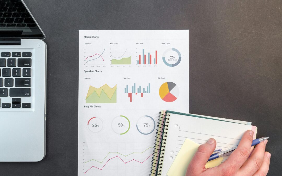 graphs notebook and laptop on desk being written on by someone planning financials